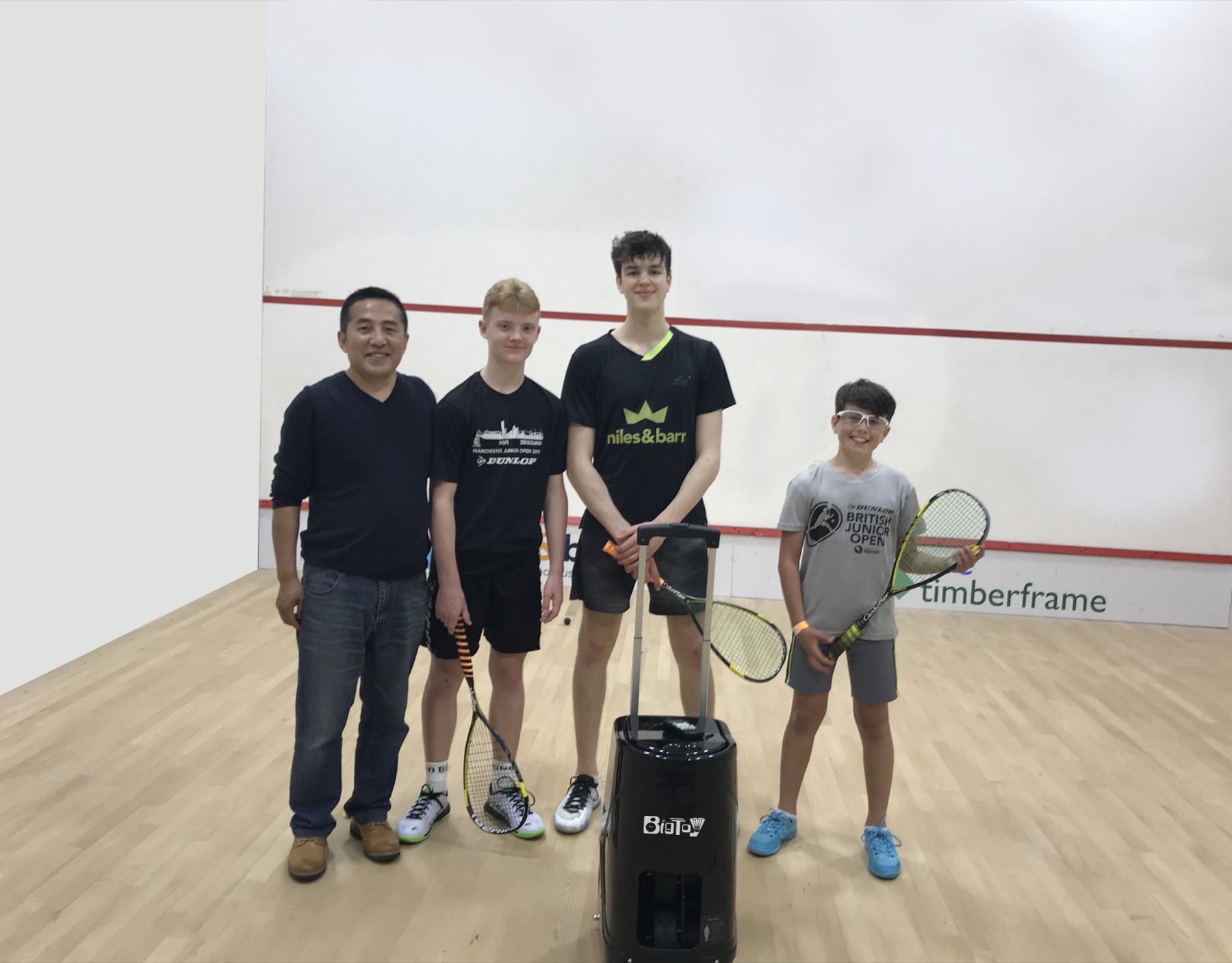 Squash players and coach with a Big Toy squash ball machine on court